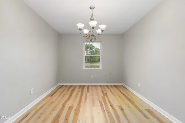 a view of an empty room with window and chandelier fan