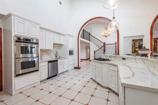 a kitchen with cabinets appliances and a chandelier