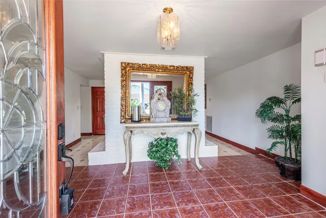a view of a hallway with wooden floor and a chandelier
