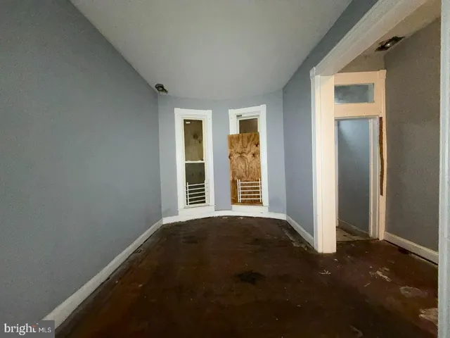 an empty room with wooden floor closet and windows