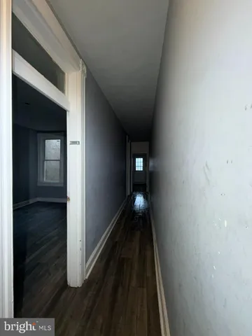a view of a hallway with wooden floor and a living room