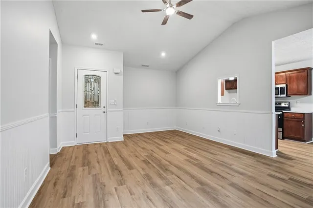 a view of empty room with wooden floor and fan