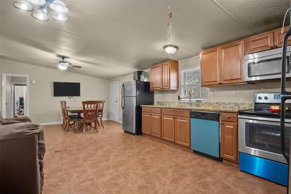 a kitchen with stainless steel appliances granite countertop a stove top oven a sink dishwasher a dining table and chairs with wooden floor