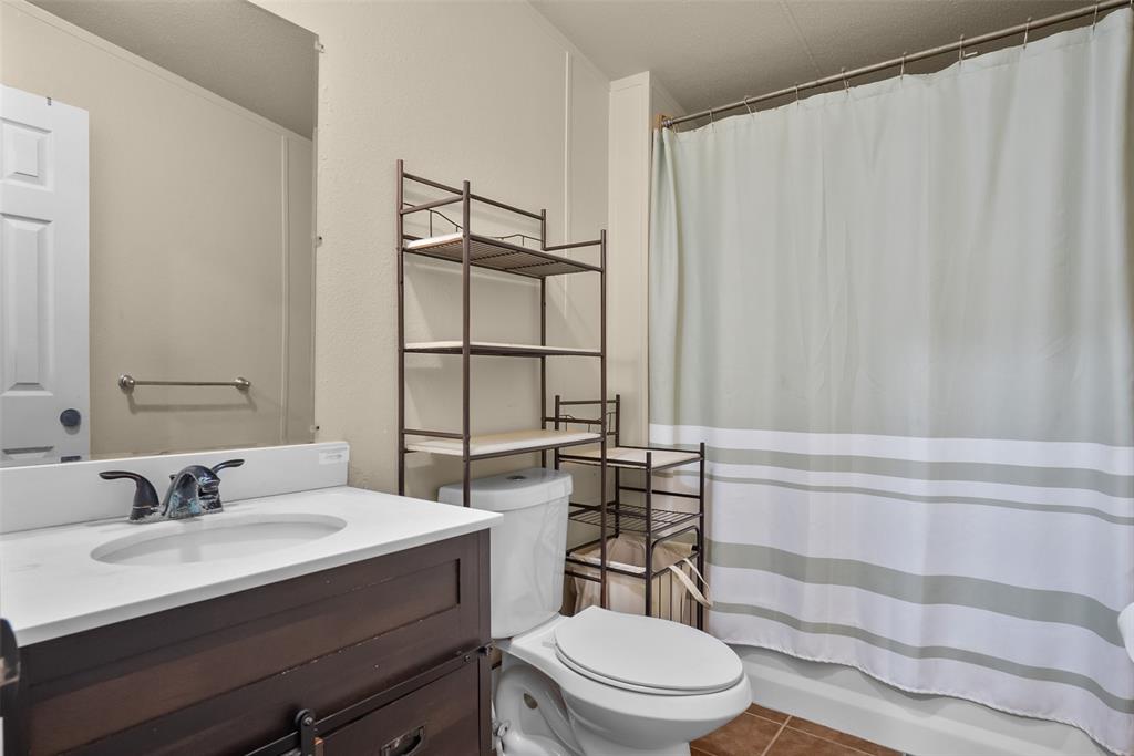 353 Prairie Lane Azle, TX 76020 - Photo 23 of 36 a bathroom with a sink a toilet a mirror and shower curtain