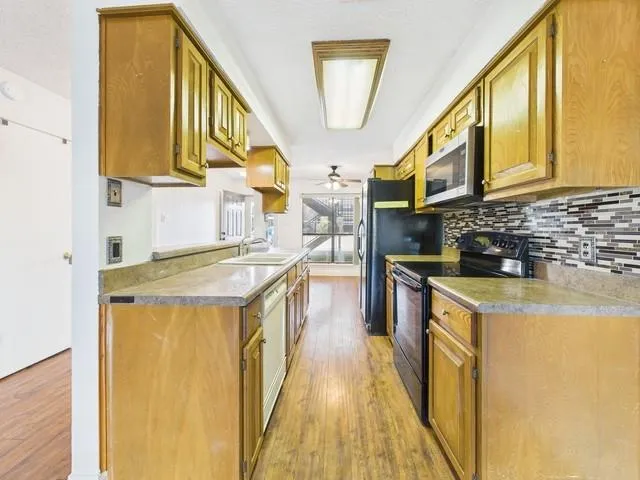 a kitchen with stainless steel appliances granite countertop a sink a stove and a refrigerator
