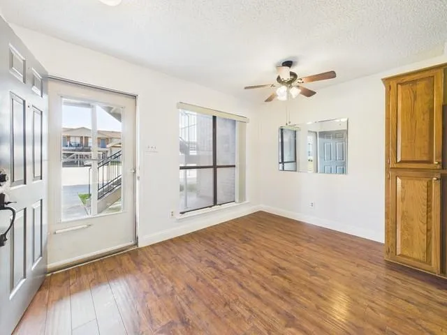 a view of empty room with wooden floor and fan