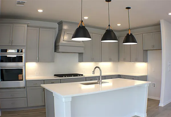 a kitchen with stainless steel appliances a sink a wooden floor and a sink