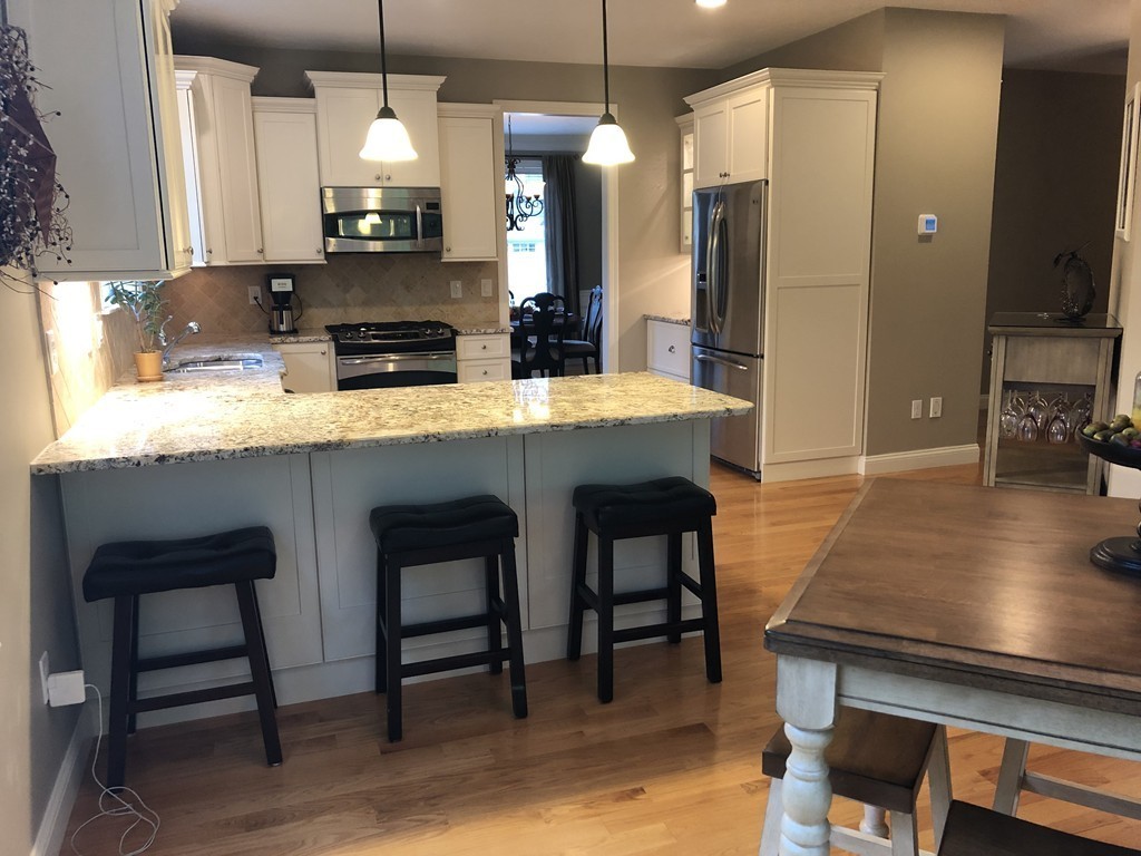 6 Adams Farm Road, Unit 6 Shrewsbury, MA 01545 - Photo 14 of 38 a kitchen with stainless steel appliances granite countertop a table chairs sink and wooden floor
