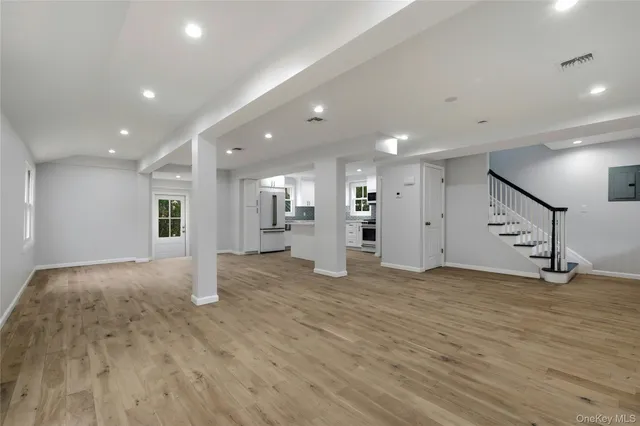 a view of an empty room with wooden floor and stairs