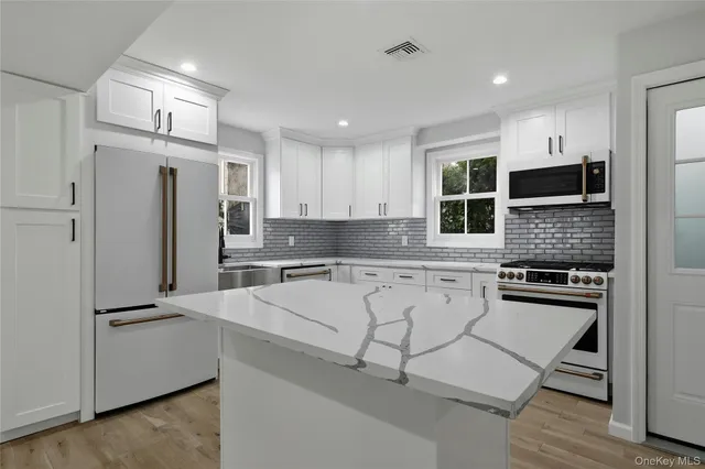a view of kitchen with kitchen island wooden floor center island and stainless steel appliances