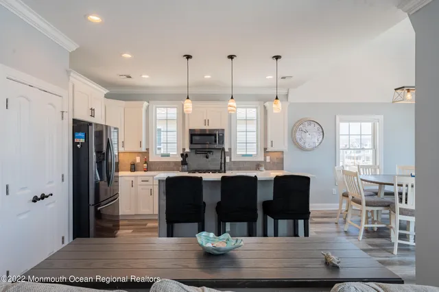 a kitchen with stainless steel appliances granite countertop a table chairs and a refrigerator