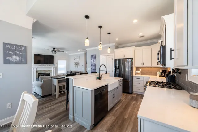 a large kitchen with stainless steel appliances a stove a sink dishwasher a refrigerator white cabinets and wooden floor