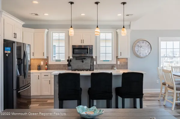 a kitchen with stainless steel appliances kitchen island granite countertop a refrigerator a stove a sink and a chairs