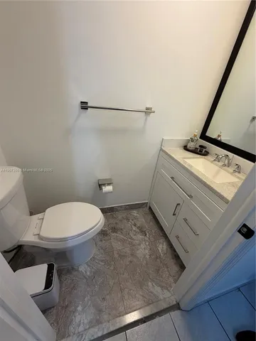 a bathroom with a granite countertop toilet and a sink