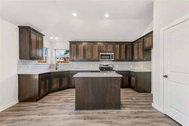 a kitchen with stainless steel appliances granite countertop a stove top oven sink and cabinets