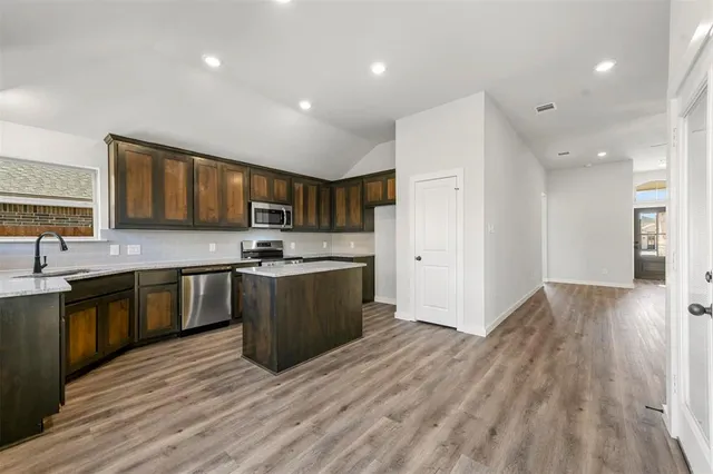 a large kitchen with stainless steel appliances granite countertop a refrigerator and a stove top oven