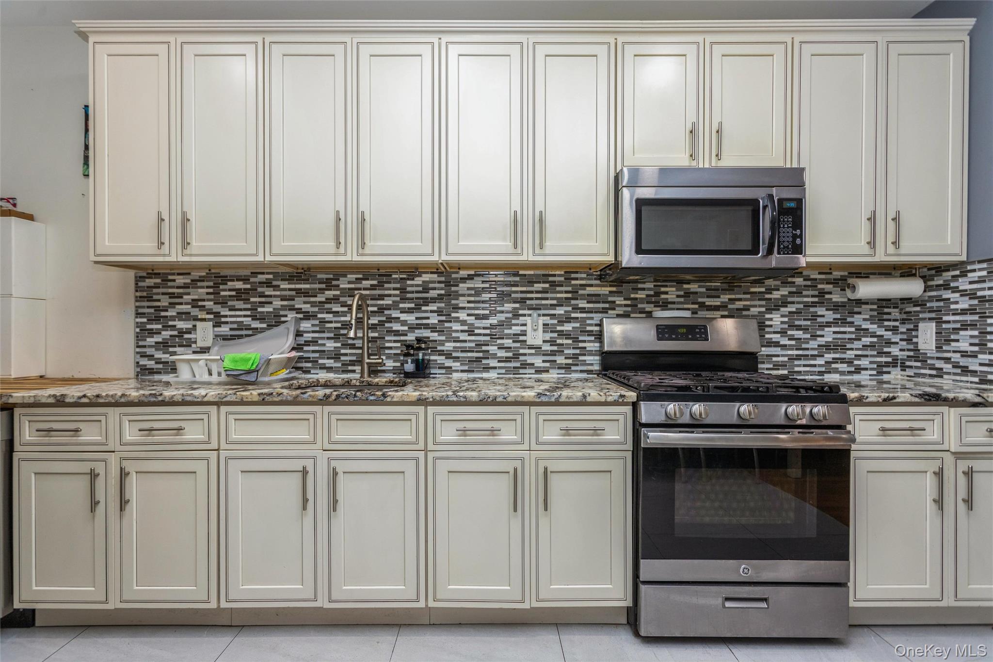 327 North 7th Avenue Mount Vernon, NY 10550 - Photo 21 of 32 a kitchen with granite countertop white cabinets and stainless steel appliances