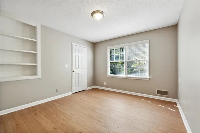 an empty room with wooden floor and windows