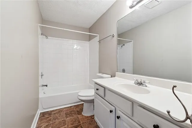 a bathroom with a granite countertop sink a toilet and shower