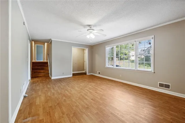 a view of an empty room with a window and wooden floor