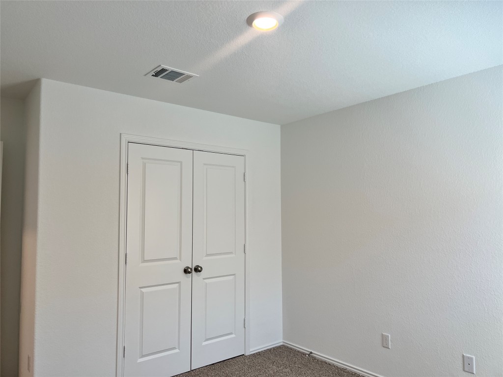 115 Canley Loop Hutto, TX 78634 - Photo 11 of 18 Unfurnished bedroom featuring carpet, a closet, and a textured ceiling