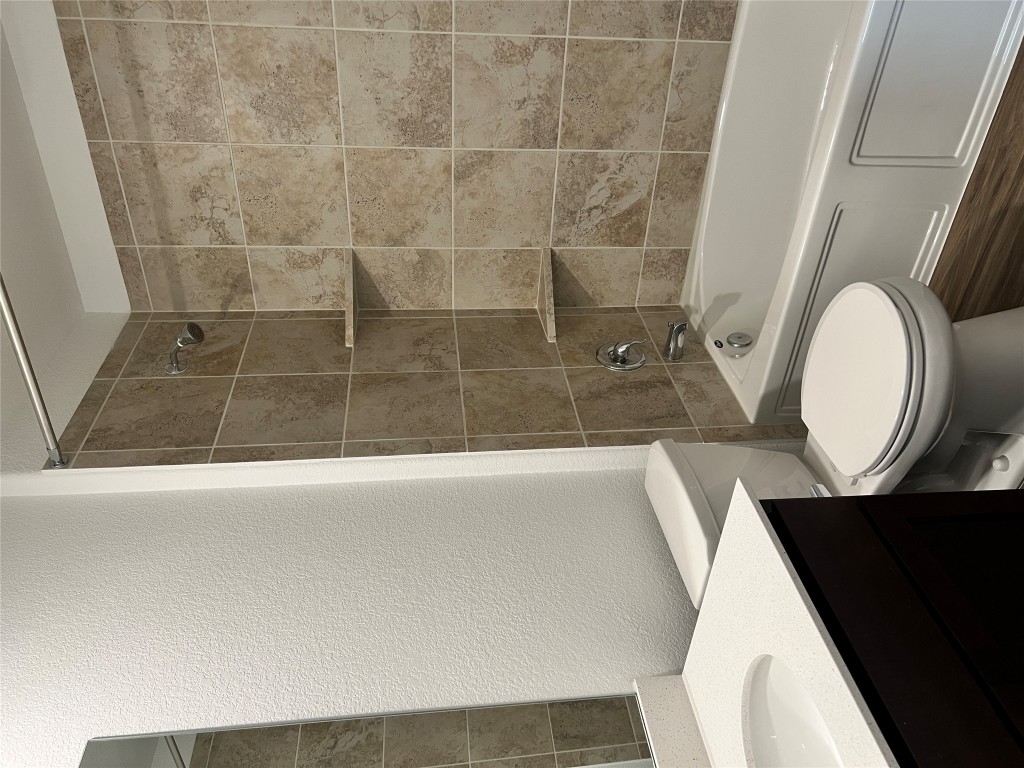 115 Canley Loop Hutto, TX 78634 - Photo 13 of 18 Bathroom featuring vanity, a textured wall, tub / shower combination, and dark wood-style floors
