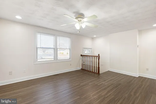 an empty room with wooden floor fan and windows