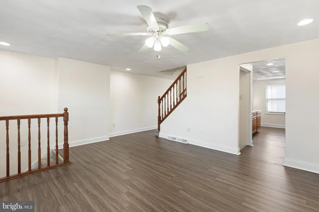 wooden floor in an empty room with a window and a bathroom