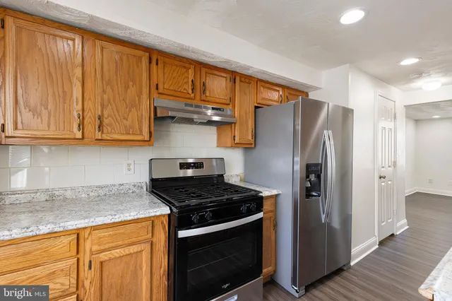 a kitchen with stainless steel appliances granite countertop a refrigerator stove and cabinets