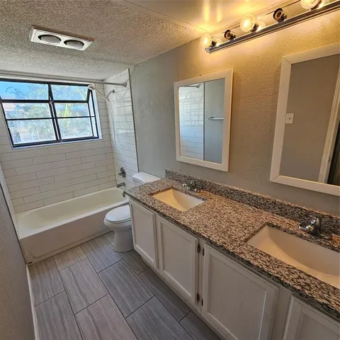 a bathroom with a granite countertop tub a sink and a large mirror