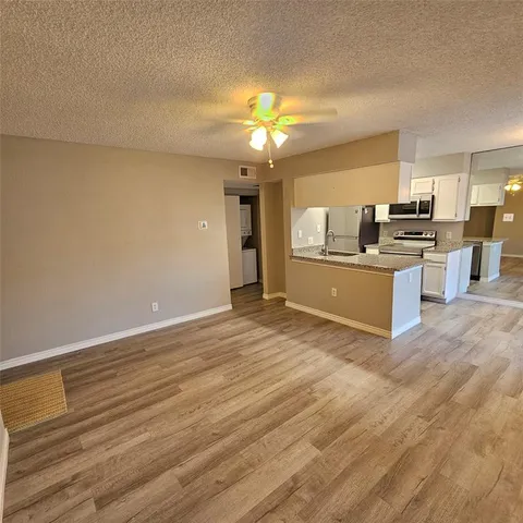 a view of a kitchen with wooden floor and stainless steel appliances