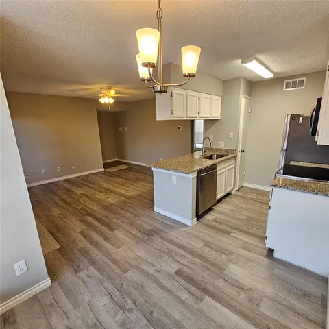 a kitchen with stainless steel appliances granite countertop a sink a stove and a wooden floors