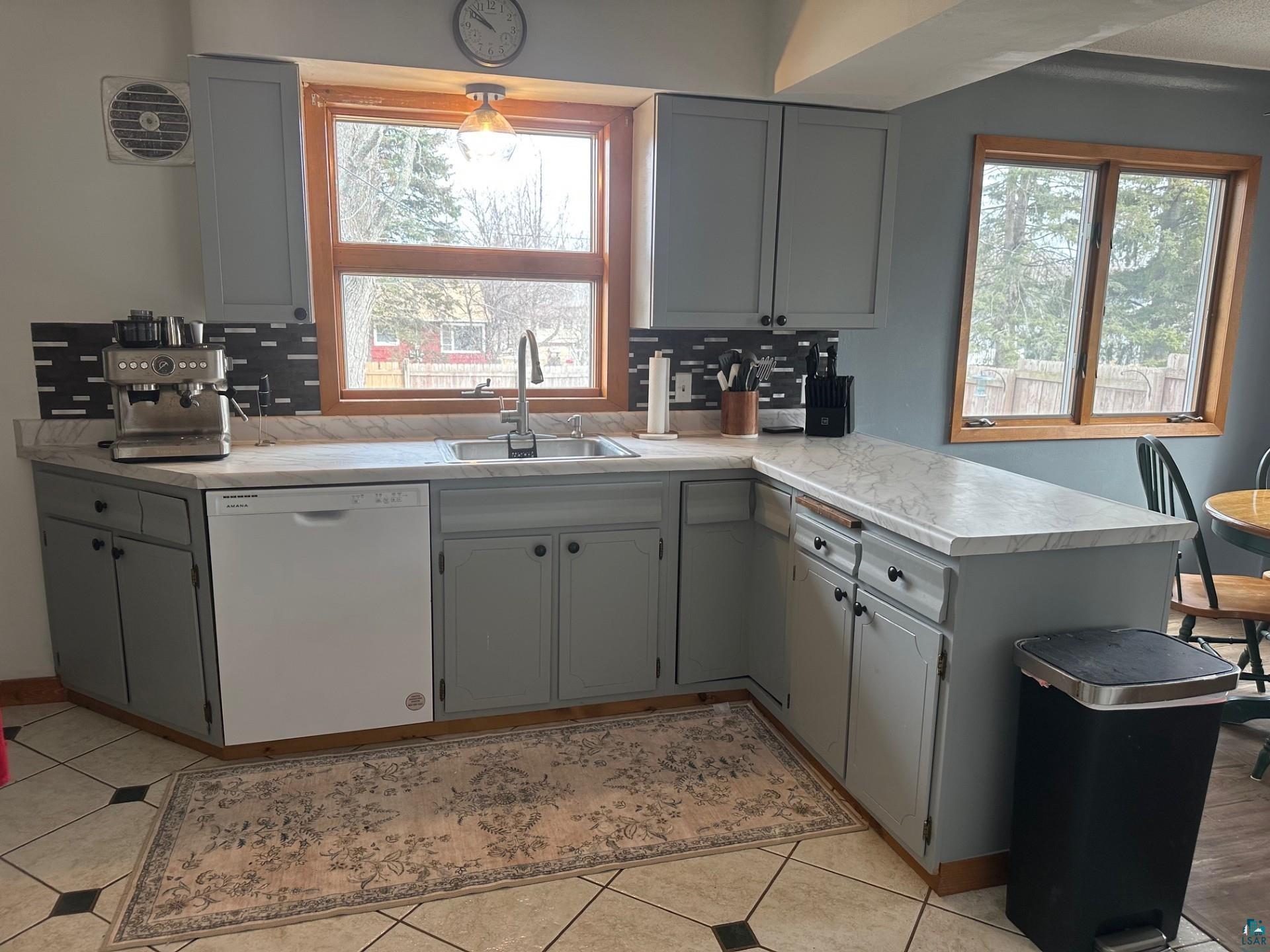 702 27th Street Cloquet, MN 55720 - Photo 4 of 25 Kitchen featuring gray cabinetry, white dishwasher, light countertops, and decorative backsplash