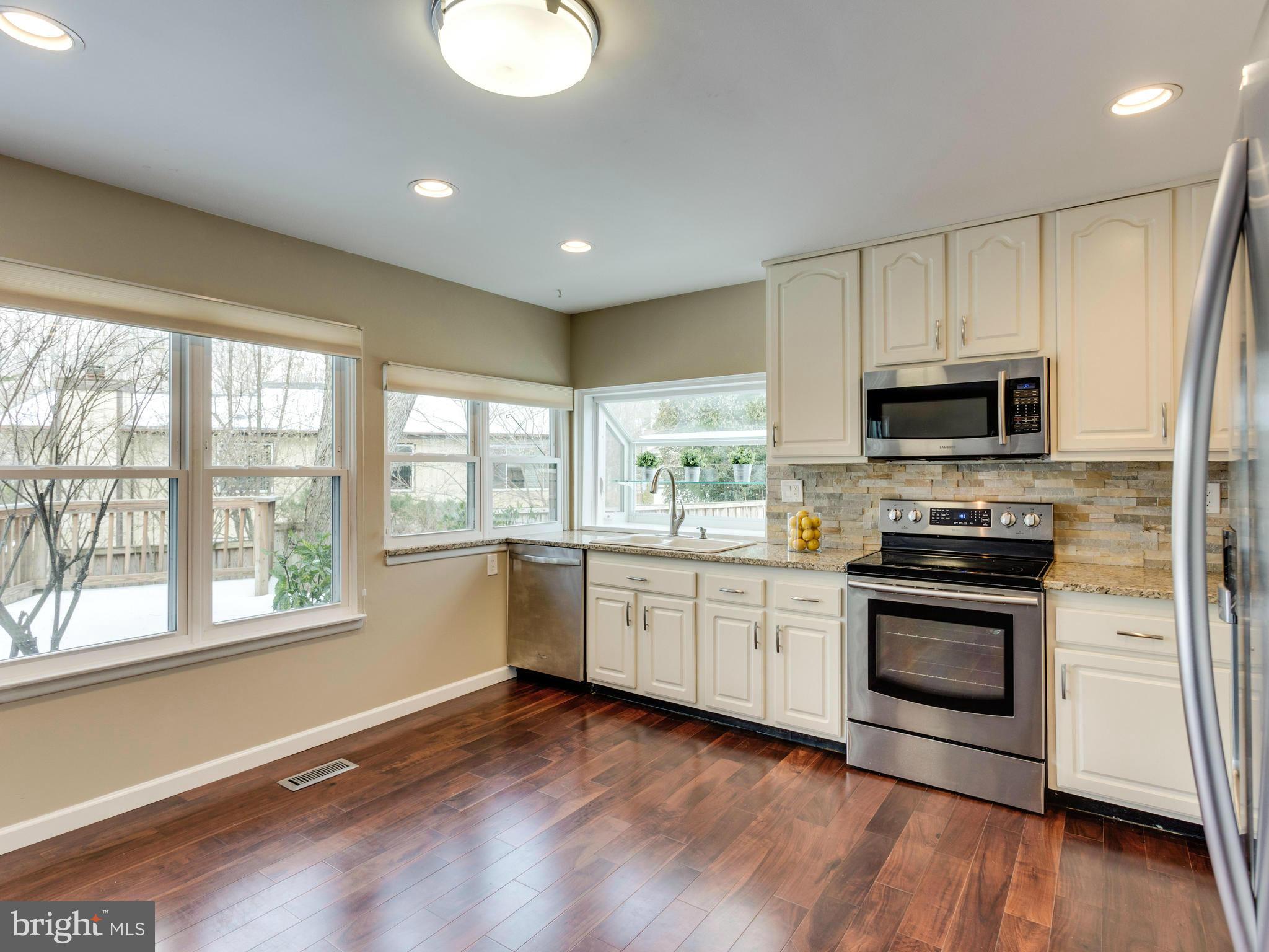 7604 Chancellor Way Springfield, VA 22153 - Photo 4 of 30 a kitchen with granite countertop a stove top oven a sink and a microwave
