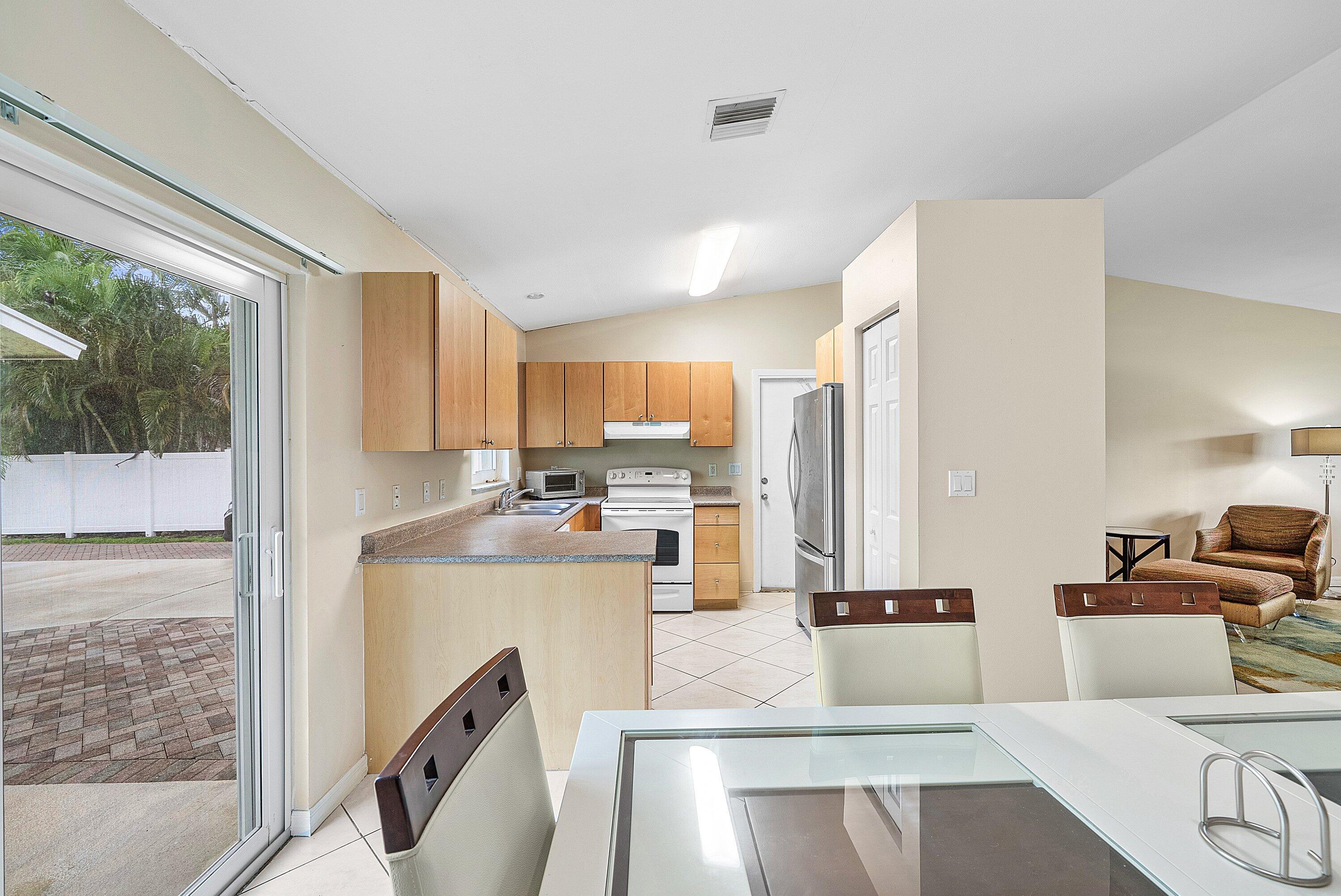 165 Northwest 8th Street Boca Raton, FL 33432 - Photo 11 of 42 a view of a kitchen with kitchen island stainless steel appliances wooden cabinets and refrigerator