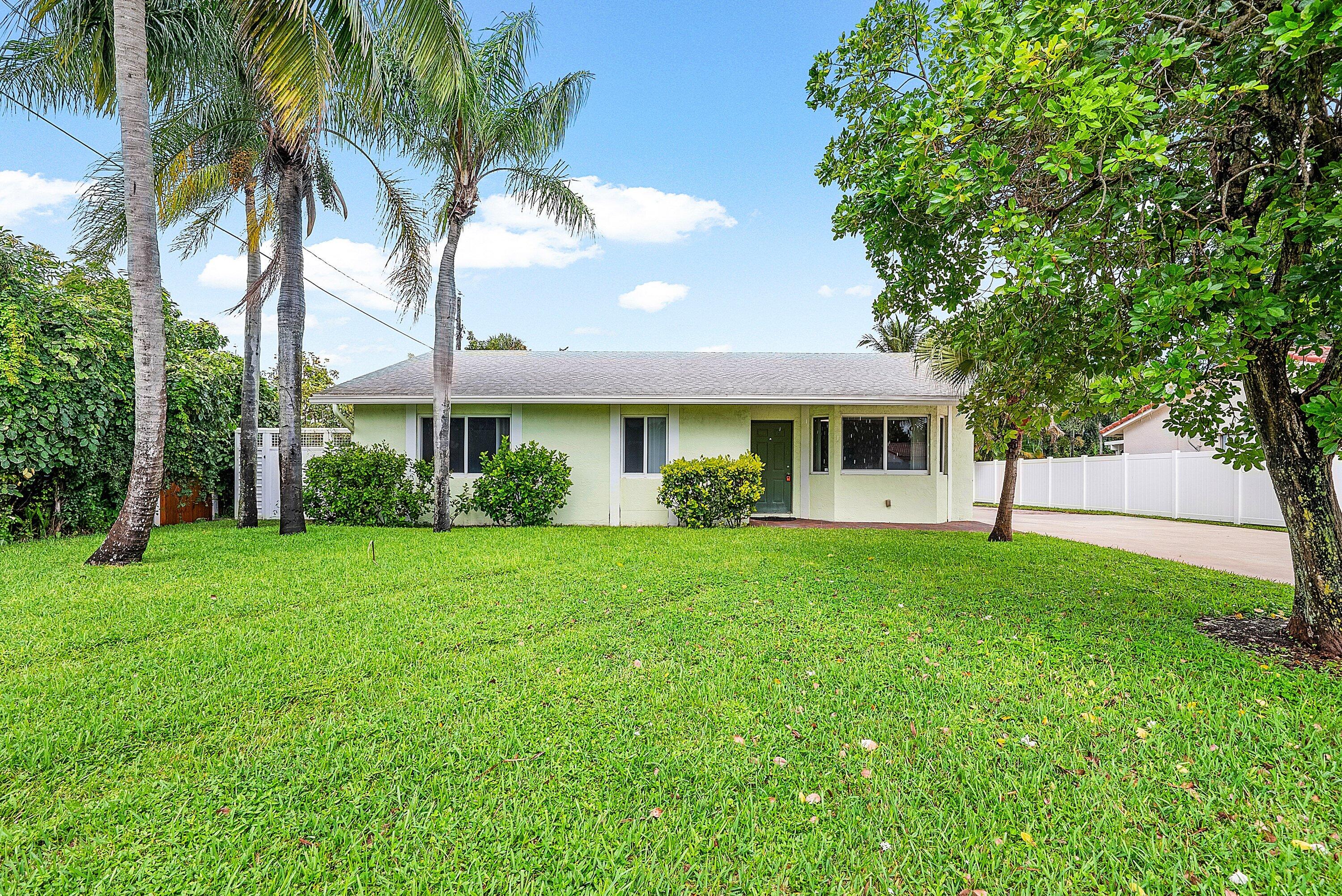165 Northwest 8th Street Boca Raton, FL 33432 - Photo 2 of 42 a front view of a house with a garden and trees