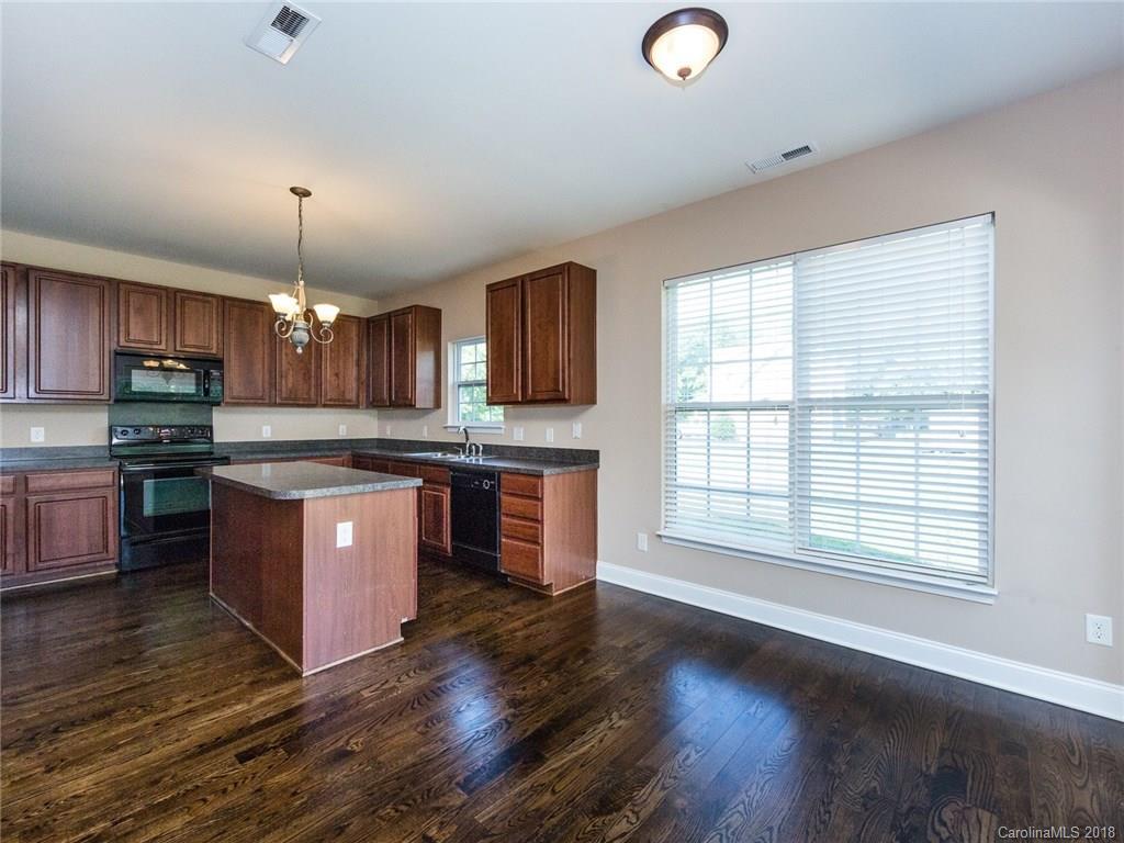 708 Baucom Road Monroe, NC 28110 - Photo 12 of 33 a kitchen with stainless steel appliances granite countertop a stove a sink dishwasher a microwave oven and a dining table with wooden floor