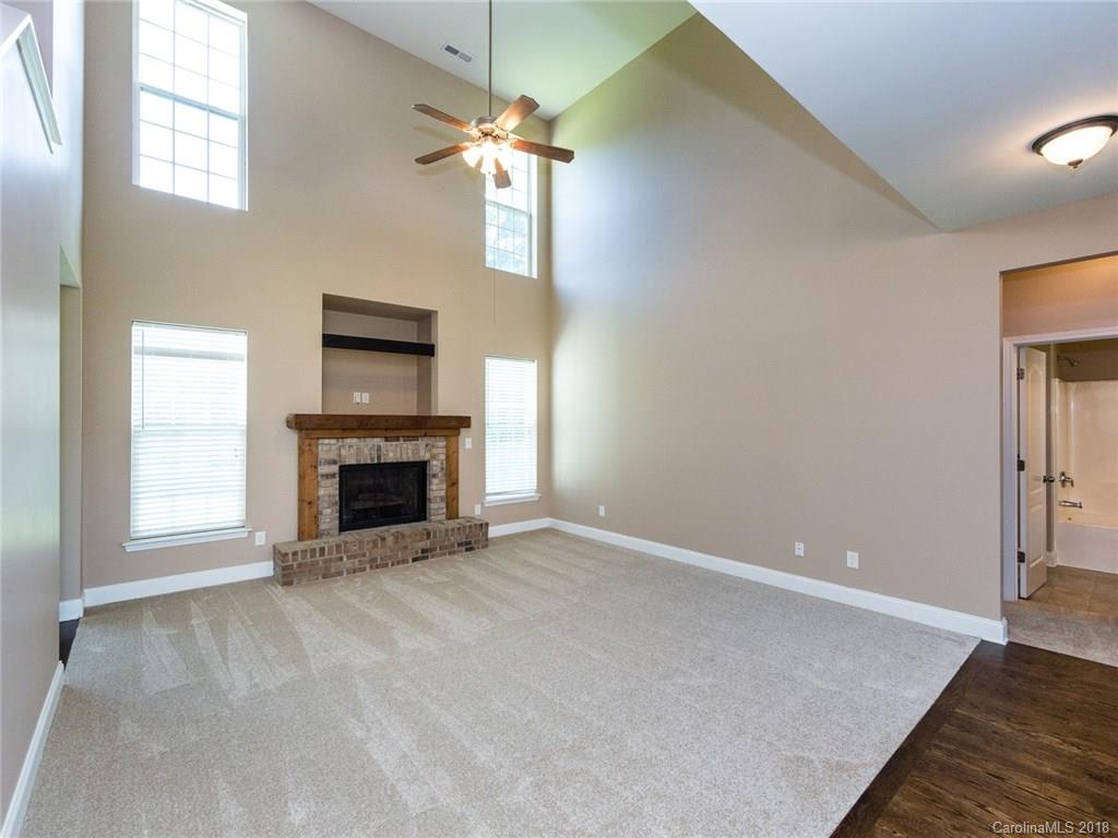708 Baucom Road Monroe, NC 28110 - Photo 8 of 33 an empty room with windows fireplace and a chandelier fan