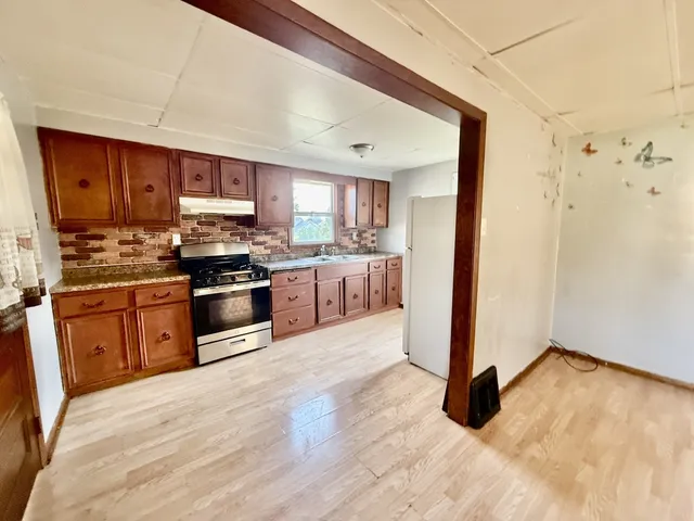 a kitchen with stainless steel appliances kitchen island granite countertop a stove a sink and a refrigerator