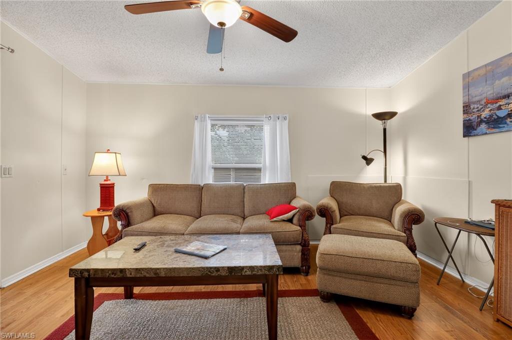 183 Oceans Boulevard, Unit 183 Naples, FL 34104 - Photo 15 of 28 Living room featuring wood finished floors, ceiling fan, and a textured ceiling