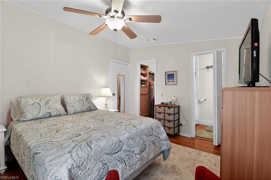 183 Oceans Boulevard, Unit 183 Naples, FL 34104 - Photo 17 of 28 Bedroom featuring a walk in closet, wood finished floors, a ceiling fan, and a textured ceiling