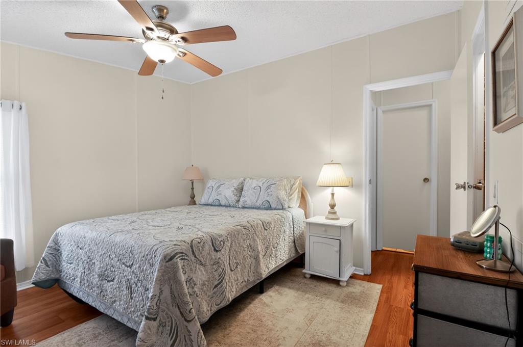 183 Oceans Boulevard, Unit 183 Naples, FL 34104 - Photo 18 of 28 Bedroom featuring ceiling fan, wood finished floors, and a textured ceiling