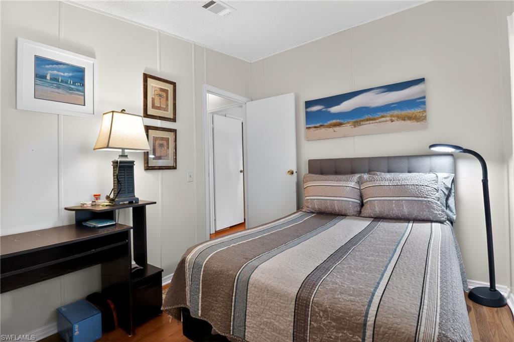 183 Oceans Boulevard, Unit 183 Naples, FL 34104 - Photo 20 of 28 Bedroom with a decorative wall and wood finished floors
