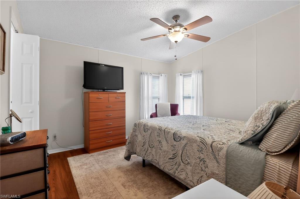 183 Oceans Boulevard, Unit 183 Naples, FL 34104 - Photo 21 of 28 Bedroom featuring wood finished floors, a ceiling fan, and a textured ceiling