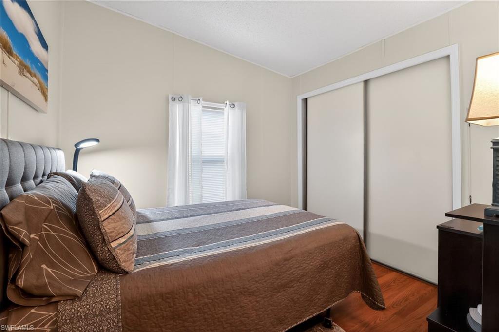 183 Oceans Boulevard, Unit 183 Naples, FL 34104 - Photo 22 of 28 Bedroom with wood finished floors, a closet, and lofted ceiling