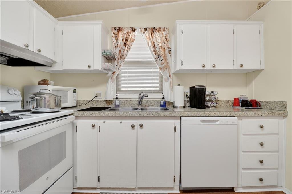 183 Oceans Boulevard, Unit 183 Naples, FL 34104 - Photo 8 of 28 Kitchen with white appliances, white cabinetry, and light countertops