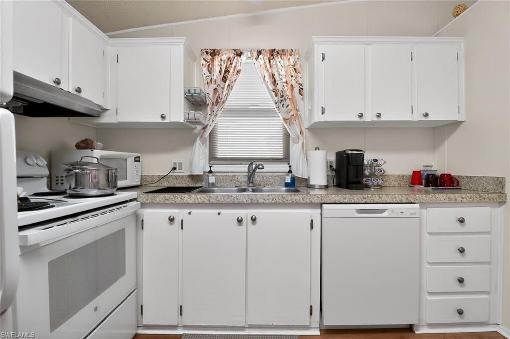 183 Oceans Boulevard, Unit 183 Naples, FL 34104 - Photo 9 of 28 Kitchen with white appliances, white cabinetry, and light countertops