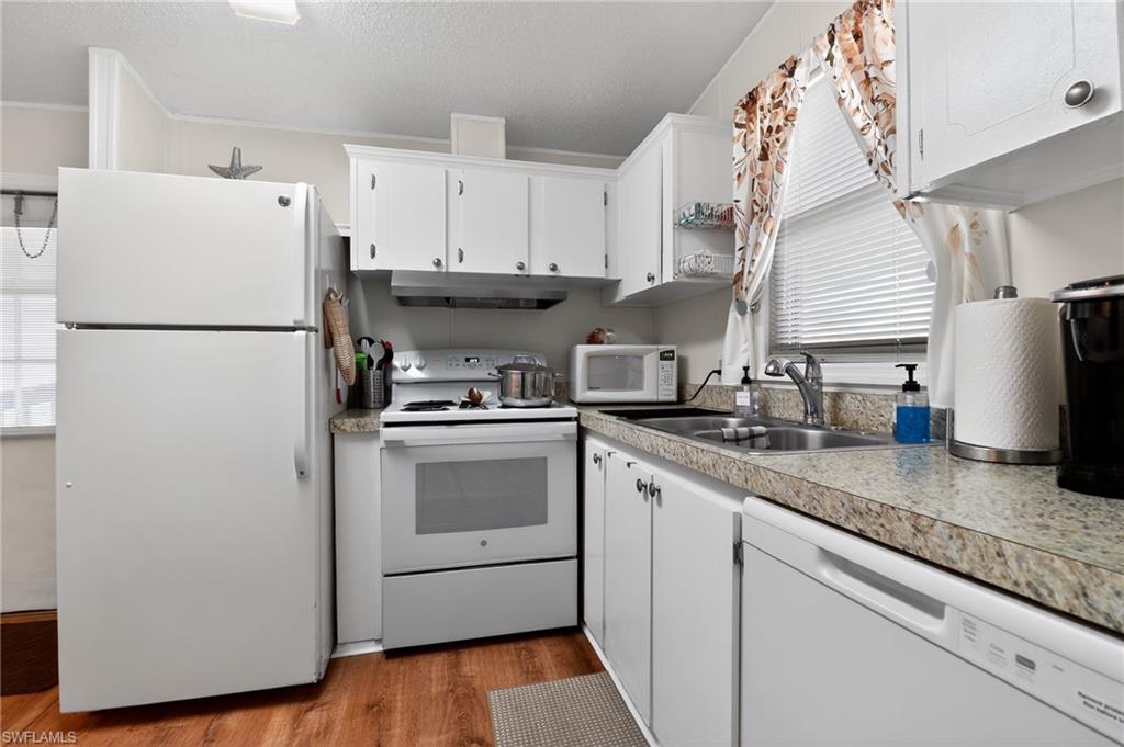 183 Oceans Boulevard, Unit 183 Naples, FL 34104 - Photo 10 of 28 Kitchen with white appliances, white cabinets, light wood finished floors, light countertops, and a textured ceiling