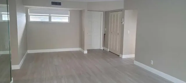 a view of an empty room with wooden floor and a window