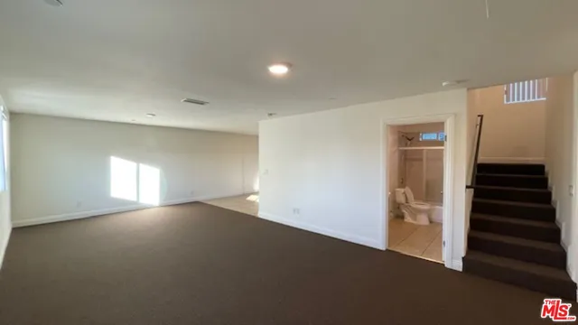 a view of an empty room with wooden floor and stairs